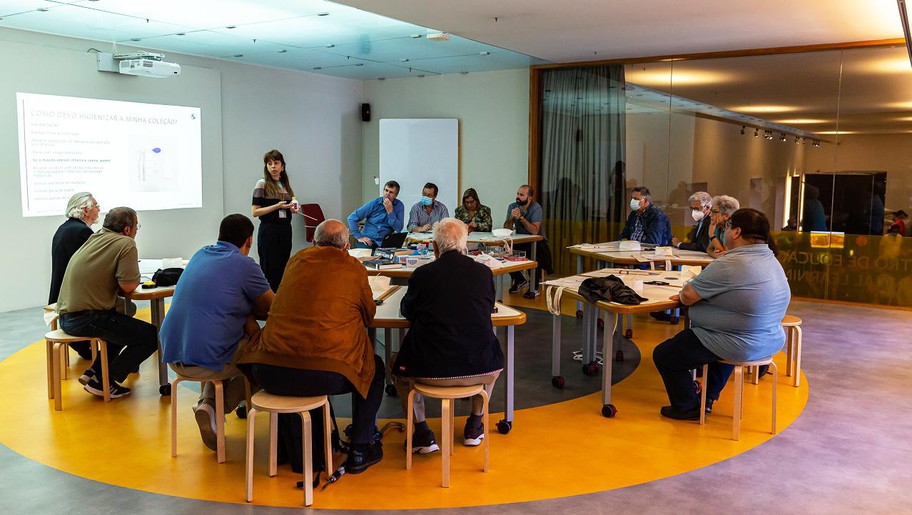 Pessoas sentadas à volta de uma mesa participam  em workshop