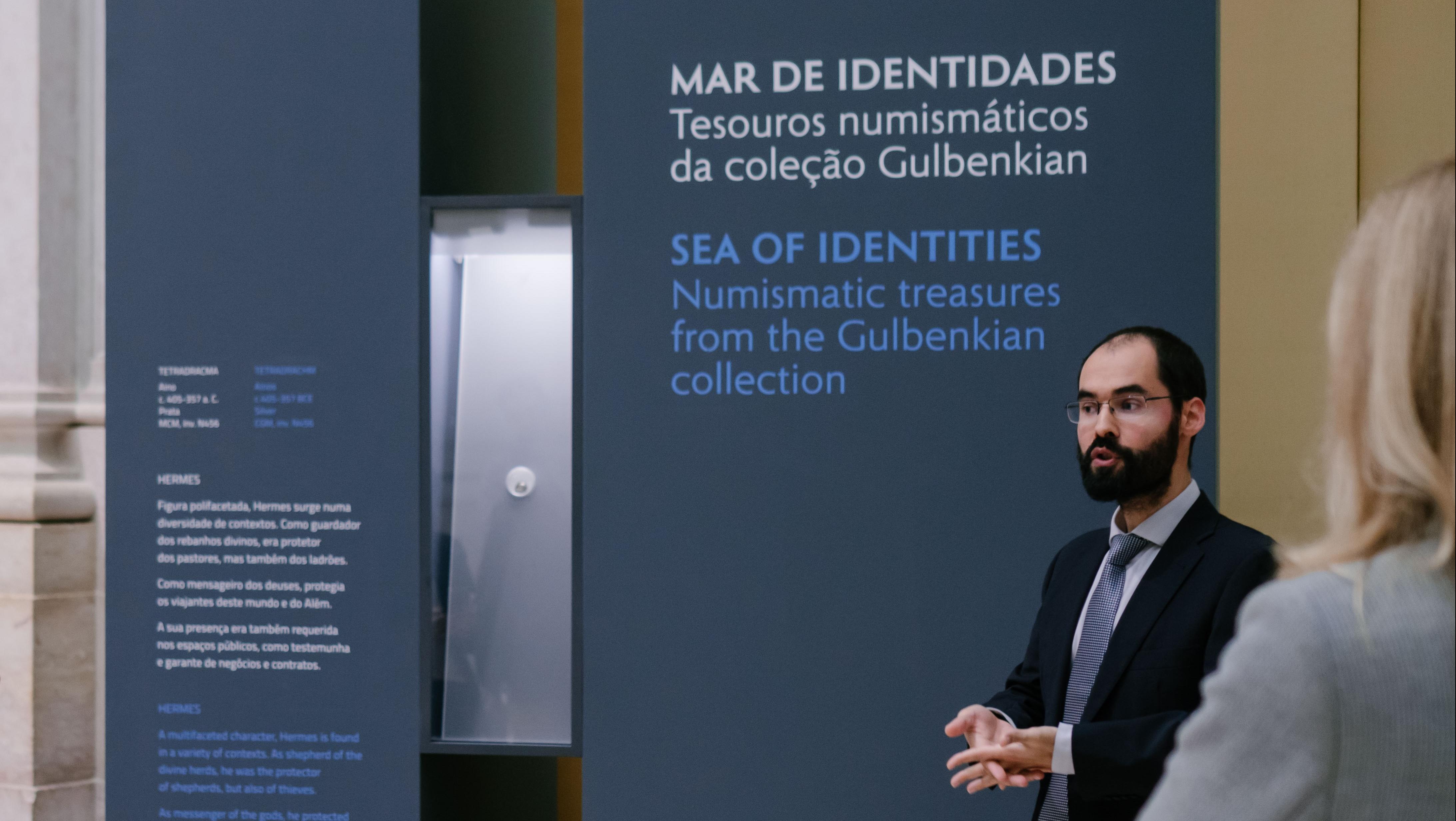Curador da exposição "Mar de identidades" orienta a visita à exposição tendo como pano de fundo um das vitrines da exposição