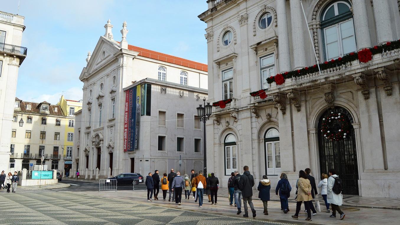 Grupo de pessoas caminha à frente dos Paços do Conselho (Câmara Municipal de Lisboa)