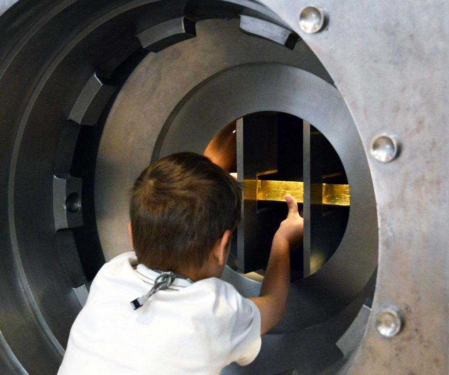 Criança toca e tenta levantar barra de ouro dentro do cofre