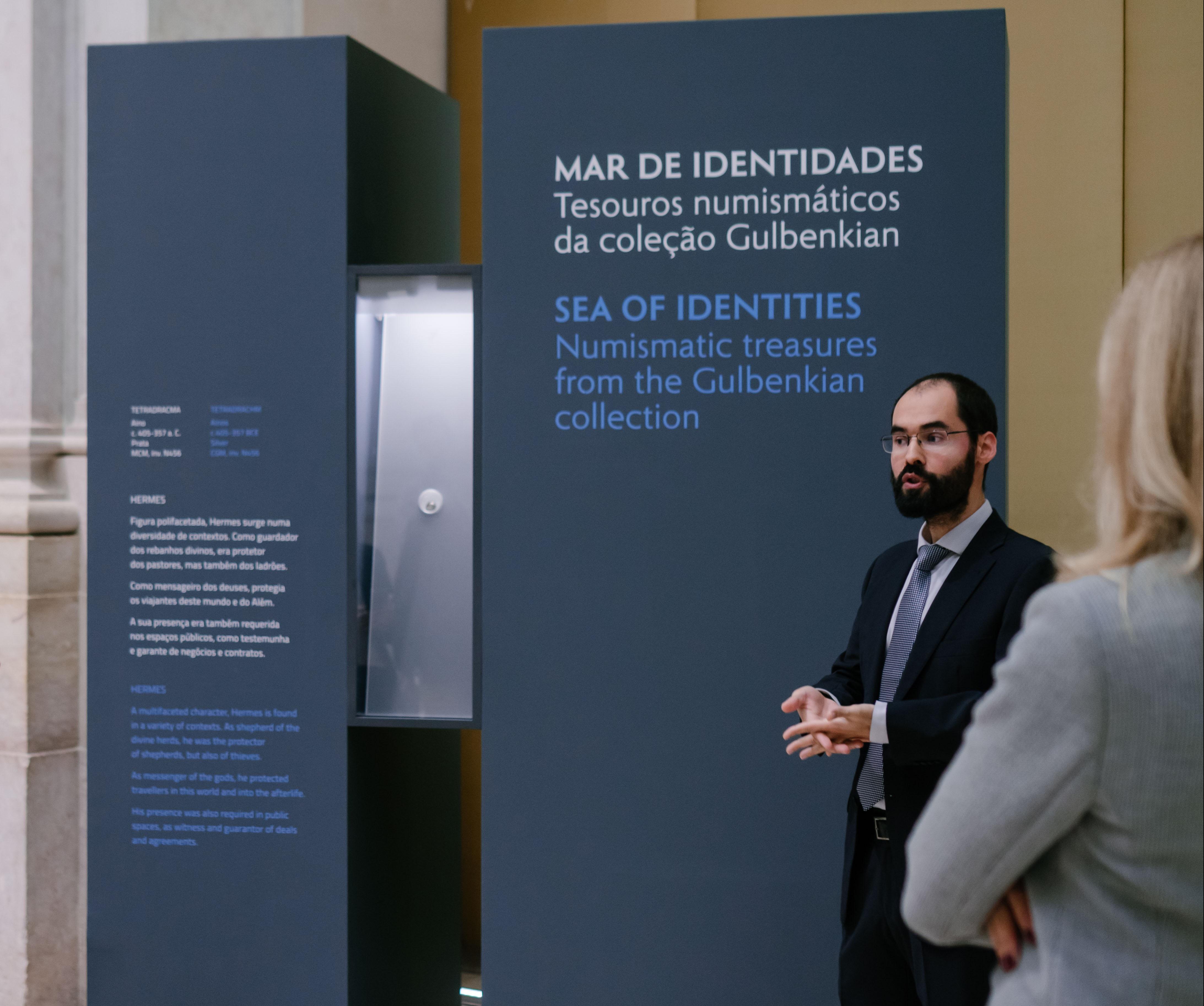 Curador da exposição "Mar de identidades" orienta a visita à exposição tendo como pano de fundo um das vitrines da exposição